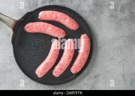 Bratwurst frais (saucisses de porc) sur une poêle gros plan sur la table de cuisine, plat avec espace de copie Banque D'Images