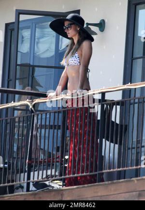 Les sœurs Hilton, Paris et Nicky sont repérées en appréciant le week-end de vacances dans leur maison de plage Malibu. Paris portait une robe rouge vif qu'elle tira pour dévoiler un bikini blanc à motif lunettes de soleil lorsqu'elle posa sur le balcon en prenant des photos avec son iPhone. Nicky portait une robe d'été verte. Malibu, Californie 6 juillet 2014. Banque D'Images