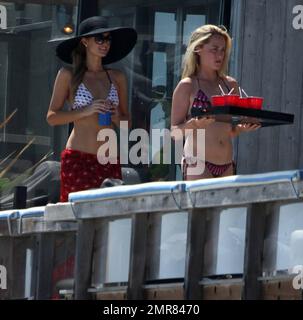 Les sœurs Hilton, Paris et Nicky sont repérées en appréciant le week-end de vacances dans leur maison de plage Malibu. Paris portait une robe rouge vif qu'elle tira pour dévoiler un bikini blanc à motif lunettes de soleil lorsqu'elle posa sur le balcon en prenant des photos avec son iPhone. Nicky portait une robe d'été verte. Malibu, Californie 6 juillet 2014. Banque D'Images