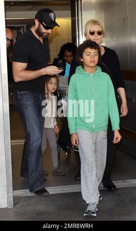 Un Hugh Jackman barbu arrive à LAX à bord d'un vol de New York avec sa famille, sa femme Deborra-Lee Furness et leurs enfants, son fils Oscar, 10 ans, et sa fille Ava, 5 ans. Jackman, qui semblait très détendu et heureux, conduit le chemin à travers l'aéroport tenant la main d'Ava et réconfortant Oscar qui semblait un peu méfiant de l'attention. Une fois à l'extérieur, Hugh a envoyé un message texte sur son téléphone cellulaire et a bavardé avec un fan alors qu'il se tenait près des bagages de la famille à leur SUV d'attente. Los Angeles, Californie. 12/12/10. Banque D'Images