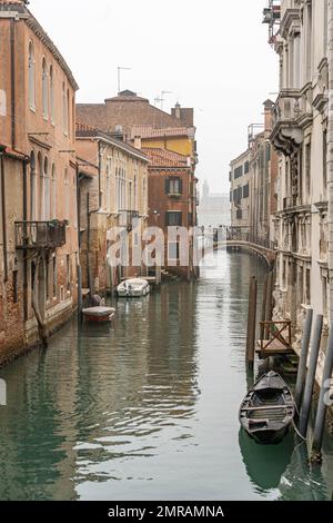 Scène du canal de Venise représentant un petit bateau dans un quartier résidentiel de Venise en hiver par un froid jour brumeux avec aucune personne ou les touristes Banque D'Images