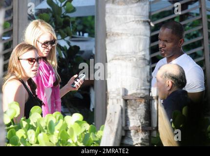EXCLUSIF !! L'acteur Jamie Foxx a eu ses amis en point de vue lorsqu'il a bavardé avec eux au bord de la piscine dans son hôtel de luxe, avec sa petite amie l'actrice Leila Arcieri, qui portait un haut rayé brillant et un short en denim sur un bikini, à ses côtés. La quartette d'amis, qui semblait juste rencontrer Arcieri, tous ont applaudi et ont fait boire un verre rapide avant de continuer. Avant de se rendre sur leur chemin, Foxx, qui semblait confortable dans un ensemble blanc de vestes, shorts et baskets, a joué au frais et s'est arrêté pour prendre des photos avec plusieurs fans, dont deux étaient de jolies jeunes femmes qu'il a semblé à l'humour comme il a cha Banque D'Images