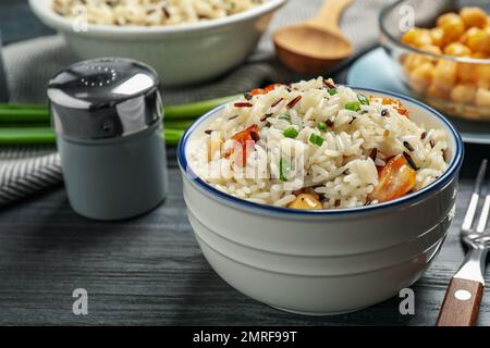 Délicieux riz pilaf avec poulet sur table en bois noir Banque D'Images