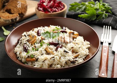 Délicieux riz pilaf aux champignons sur table noire Banque D'Images