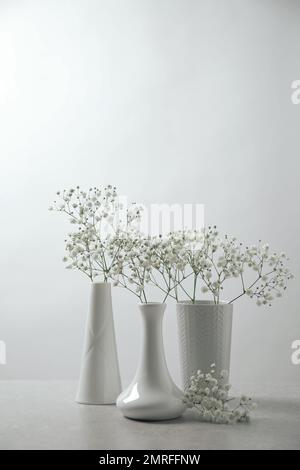 Gypsophila fleurit dans des vases sur une table sur fond blanc Banque D'Images