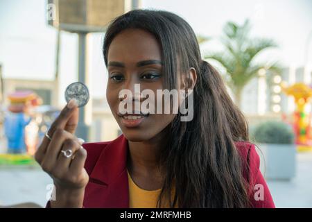 Une femme négociante afro-américaine attrayante détient une pièce de monnaie en bitcoin. Concentrez-vous sur son visage Banque D'Images