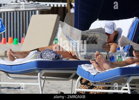 L'ancre de CBS News Katie Couric apprécie un thé glacé frais et lit le New York Times tout en prenant un bain de soleil sur la plage avec son petit ami Brooks Perlin. Miami, Floride. 01/29/11. Banque D'Images