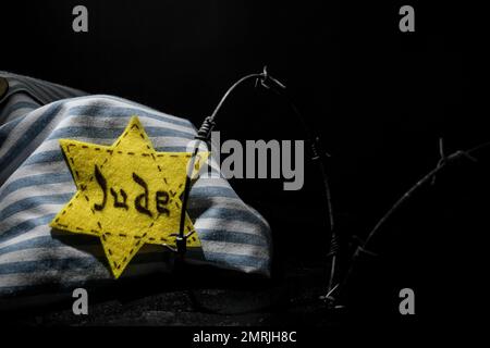 Uniforme de prisonnier, badge juif et barbelé sur fond noir avec espace pour le texte. Journée internationale de commémoration de l'Holocauste Banque D'Images