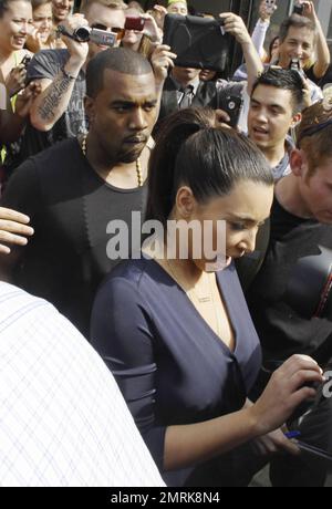 Kim Kardashian, petit ami Kanye West, qui portait son collier taillé dans sa chemise pour la sécurité, et la sœur Khloe Kardashian quittent la grande ouverture de leur nouvelle boutique Dash à West Hollywood. Kim et Kanye ont été aidés à Rolls Royce de Kim par des gardes du corps qui ont aidé à gérer l'énorme foule de fans qui s'étaient rassemblés à l'extérieur du magasin. Lors de l'événement, Kim a reçu un billet pour se garer dans une aire de stationnement non disponible. Los Angeles, Californie. 13th juillet 2012. Banque D'Images