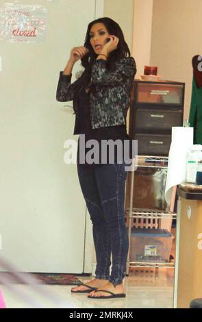 Kim Kardashian parle sur son téléphone portable et porte un Jean skinny lavé à l'acide tendance lorsqu'elle arrive dans un salon de manucure de Beverly Hills. Los Angeles, Californie. 03/02/10. Banque D'Images