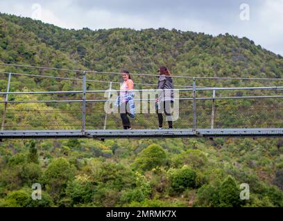 Deux femmes franchissent une passerelle au-dessus de la rivière Otaki à Kapiti, en Nouvelle-Zélande Banque D'Images