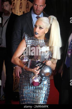 Dans une tenue tendance typique ornée d'sourcils verts étincelants, d'une croix argentée au-dessus de son nez, d'un rouge à lèvres bleu et d'une coiffure multi-couches, Lady Gaga présente ses multiples récompenses remportées aux MTV Europe Music Awards 2011 à l'Odyssey Arena de Belfast, en Irlande du Nord. 6th novembre 2011. . Banque D'Images