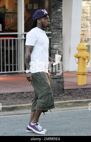 EXCLUSIF !! Le rappeur et l'ex-condamné Lil Wayne fume un cigare et transporte un verre dans les rues de Miami Beach. Le chanteur tatoué, qui a été libéré de la prison de l'île Rikers à New York en novembre dernier, s'est ensuite rendu dans une voiture avec chauffeur. Miami, Floride. 01/04/11. . Banque D'Images