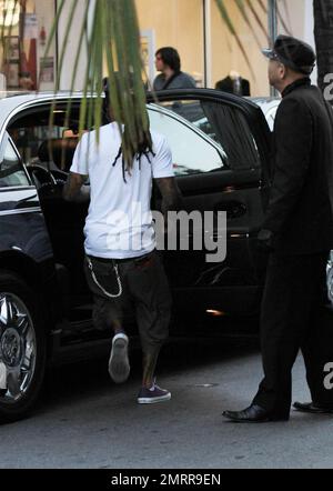 EXCLUSIF !! Le rappeur et l'ex-condamné Lil Wayne fume un cigare et transporte un verre dans les rues de Miami Beach. Le chanteur tatoué, qui a été libéré de la prison de l'île Rikers à New York en novembre dernier, s'est ensuite rendu dans une voiture avec chauffeur. Miami, Floride. 01/04/11. . Banque D'Images