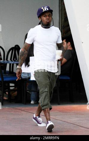 EXCLUSIF !! Le rappeur et l'ex-condamné Lil Wayne fume un cigare et transporte un verre dans les rues de Miami Beach. Le chanteur tatoué, qui a été libéré de la prison de l'île Rikers à New York en novembre dernier, s'est ensuite rendu dans une voiture avec chauffeur. Miami, Floride. 01/04/11. . Banque D'Images