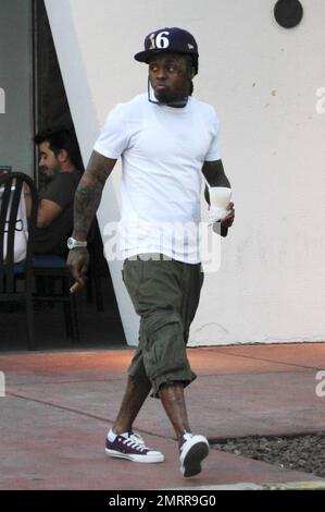 EXCLUSIF !! Le rappeur et l'ex-condamné Lil Wayne fume un cigare et transporte un verre dans les rues de Miami Beach. Le chanteur tatoué, qui a été libéré de la prison de l'île Rikers à New York en novembre dernier, s'est ensuite rendu dans une voiture avec chauffeur. Miami, Floride. 01/04/11. . Banque D'Images