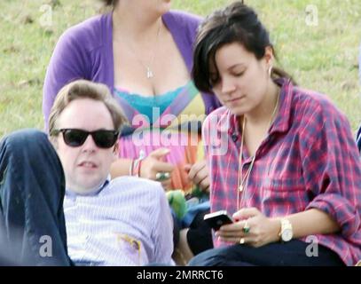 EXCLUSIF !! Premières photos de la chanteuse pop enceinte Lily Allen au Big Chill Festival avec le petit ami Sam Cooper et son chien adopté Honey. Le couple, qui vient d'annoncer qu'ils ont leur premier enfant ensemble, décontracté sur l'herbe tandis que Lily a vérifié son téléphone cellulaire. Allen est sur le point de jouer la garniture de pavillon ce soir pendant le festival de musique de week-end qui s'est tenu à Eastnor Castle Deer Park près de Ledbury, probablement l'un de ses derniers concerts avant qu'elle ne prenne une pause pour devenir mère. Herefordshire, Royaume-Uni. 08/08/10 . Banque D'Images