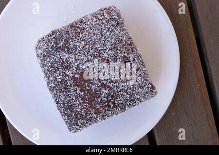 Une ladington au chocolat traditionnel sur une assiette dans une boulangerie en Australie méridionale. Banque D'Images