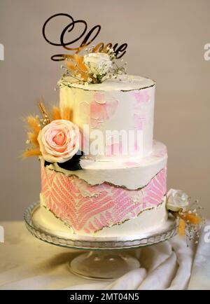 gâteau de mariage superposé décoré de fleurs fraîches sur un fond sombre Banque D'Images