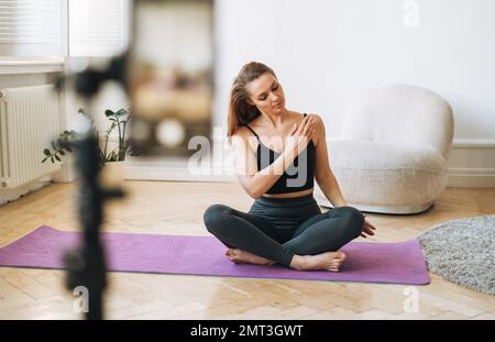 Jeune femme de forme physique blogger faisant des exercices et l'enregistrement vidéo sur téléphone mobile en studio Banque D'Images