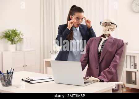 Jeune femme travaillant avec le squelette au bureau Banque D'Images