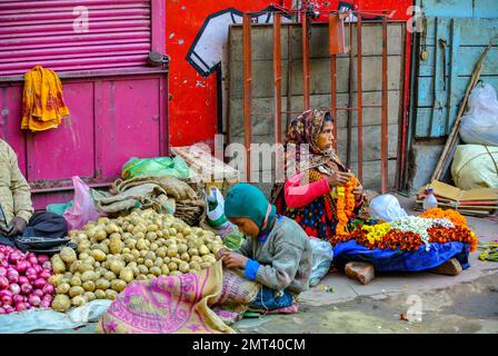 Varanasi, Uttar Pradesh, Inde, Un marchand de légumes vendant des pommes de terre et des fleurs dans la rue. Banque D'Images