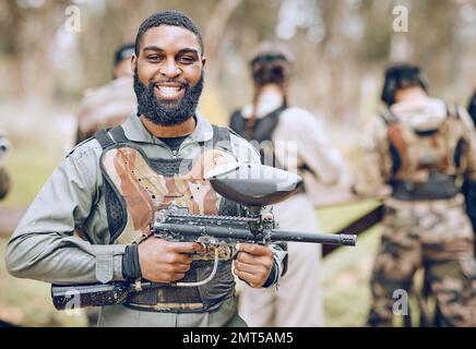 Paintball, pistolet et portrait d'homme noir avec sourire prêt pour le jeu, le match et le tir de bataille en plein air. Sports extrêmes, aventure et homme dans Banque D'Images