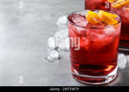 Cocktail Negroni frais avec zeste d'orange sur table grise, gros plan. Espace pour le texte Banque D'Images