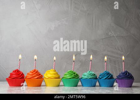 De délicieux petits gâteaux d'anniversaire avec des bougies allumées sur la table Banque D'Images