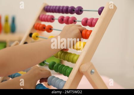 Enfant mignon jouant avec abacus en bois à table dans la chambre, gros plan Banque D'Images