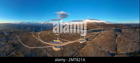 Moulins à vent sur les collines pendant le coucher du soleil. Énergies renouvelables, énergies vertes. Montagnes en arrière-plan avec de la neige. Énergie éolienne et écologique. Banque D'Images