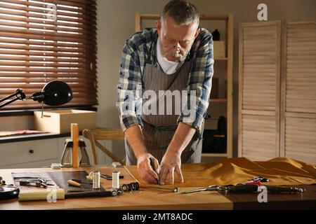 Homme travaillant avec un morceau de cuir dans l'atelier Banque D'Images