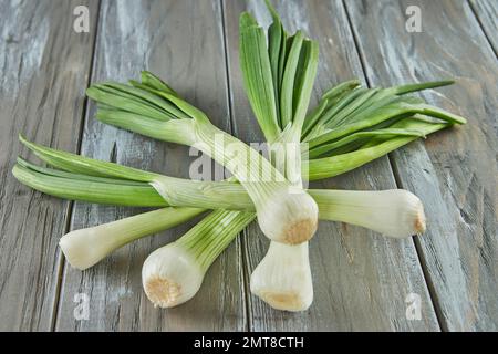 Poireaux frais empilés sur fond gris en bois. Gros plan. Banque D'Images