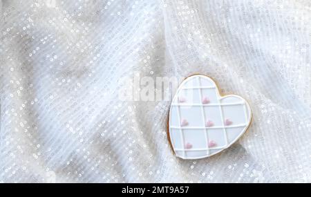 Pain d'épice de Saint-Valentin en forme de coeur sur fond blanc avec paillettes. Vue de dessus Banque D'Images