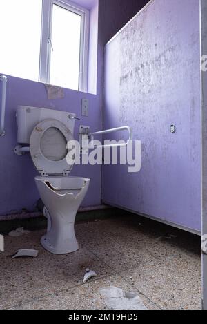 Image des toilettes gériatriques vandalisées et de la main courante de l'intérieur de l'armoire de l'hôpital abandonné abandonné. Banque D'Images