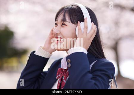 Portrait d'étudiant japonais de lycée avec fleurs de cerisier en pleine floraison Banque D'Images