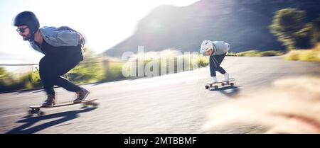 Sports, vitesse et patinage de longue durée rapide sur route, amis qui font des courses de descente avec un skateboard et un casque pour plus de sécurité. Aventure sportive extrême Banque D'Images