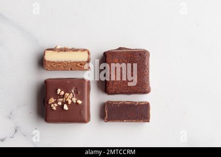 Bonbons faits main au chocolat et morceaux de bonbons coupés avec praline et truffe sur fond blanc avec photo horizontale d'espace de copie Banque D'Images