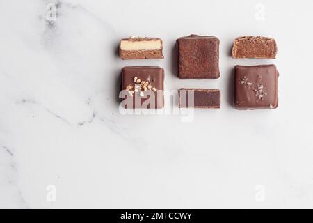 Bonbons faits main au chocolat et morceaux de bonbons coupés avec praline et truffe sur fond blanc avec photo horizontale d'espace de copie Banque D'Images