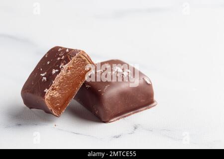 Bonbons faits main au chocolat et morceaux de bonbons coupés avec praline et truffe sur fond blanc avec photo horizontale d'espace de copie Banque D'Images