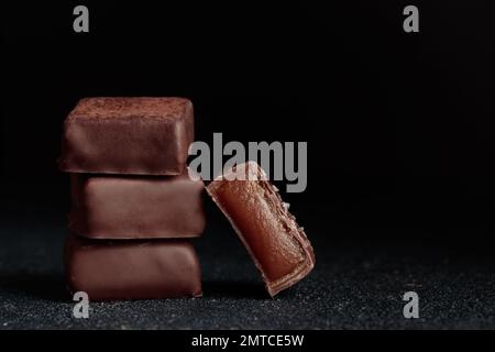 Bonbons au chocolat faits à la main et morceau de bonbons coupés au caramel sur fond noir avec photo horizontale d'espace de copie Banque D'Images