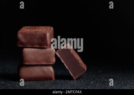 Bonbons faits à la main au chocolat et morceau de bonbon taillé avec truffe sur fond noir avec la photo horizontale d'espace de copie Banque D'Images