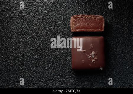 Bonbons au chocolat faits à la main et morceau de bonbons coupés au caramel sur fond noir avec photo horizontale d'espace de copie Banque D'Images