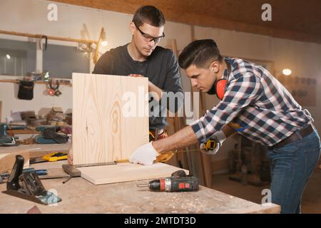 Charpentiers professionnels travaillant avec des planches en bois en atelier Banque D'Images