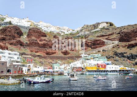 Oía, Santorini, Grèce; 22 juin 2022: Baie d'Ammoudi, Port d'Oia avec ses terrasses sur la rive et ses bateaux de pêche Banque D'Images