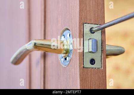 Réparation de la poignée de porte à levier avec serrure sur une porte intérieure. Banque D'Images