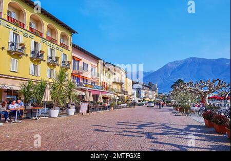 ASCONA, SUISSE - 28 MARS 2022 : la Piazza Giuseppe Motta est la promenade au bord du lac avec une ligne de restaurants touristiques extérieurs et une maison de ville historique Banque D'Images