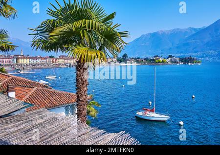 Paysage alpin et maisons anciennes d'Ascona derrière le lac majeur avec yacht blanc à voile, balançant sur les vagues, Tessin, Suisse Banque D'Images