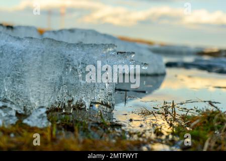 De petits morceaux de glace avec des gouttes volantes sur les rives de la rivière fondent de la chaleur au printemps. Banque D'Images