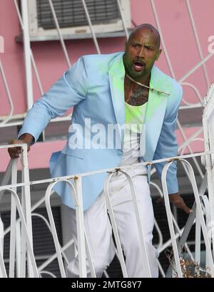 EXCLUSIF !! Portant une veste bleue pour bébé, une chemise blanche, un pantalon blanc, des chaussures blanches, un collier crucifix et ce qui semble être de la goo verte sur son visage et sa poitrine, Dwayne « The Rock » Johnson et son double stunt sont vus sur le terrain pour filmer une séquence d'action pour son prochain film « pain & gain ». Le film est réalisé par Michael Bay, réalisateur de 'Transformerss', et devrait sortir en 2013. Maimi, Floride. 14th avril 2012. Banque D'Images